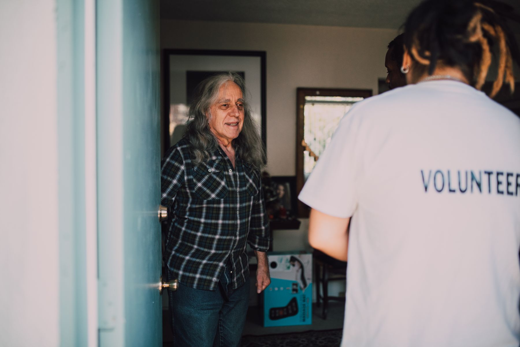 A young volunteer greeting a resident at her front door during neighborhood outreach